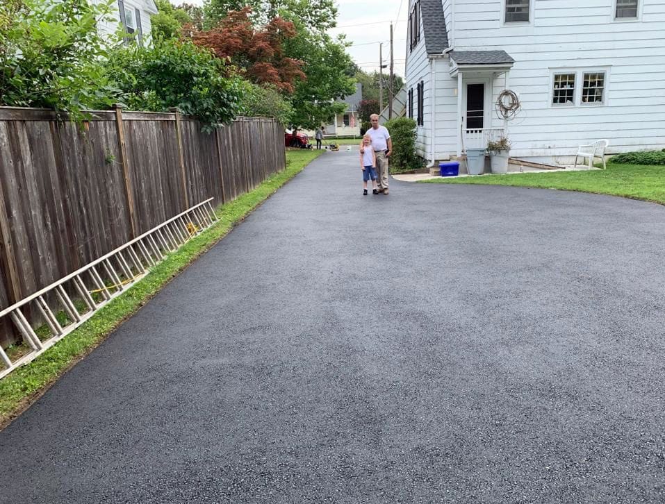 Long asphalt driveway running beside a fence