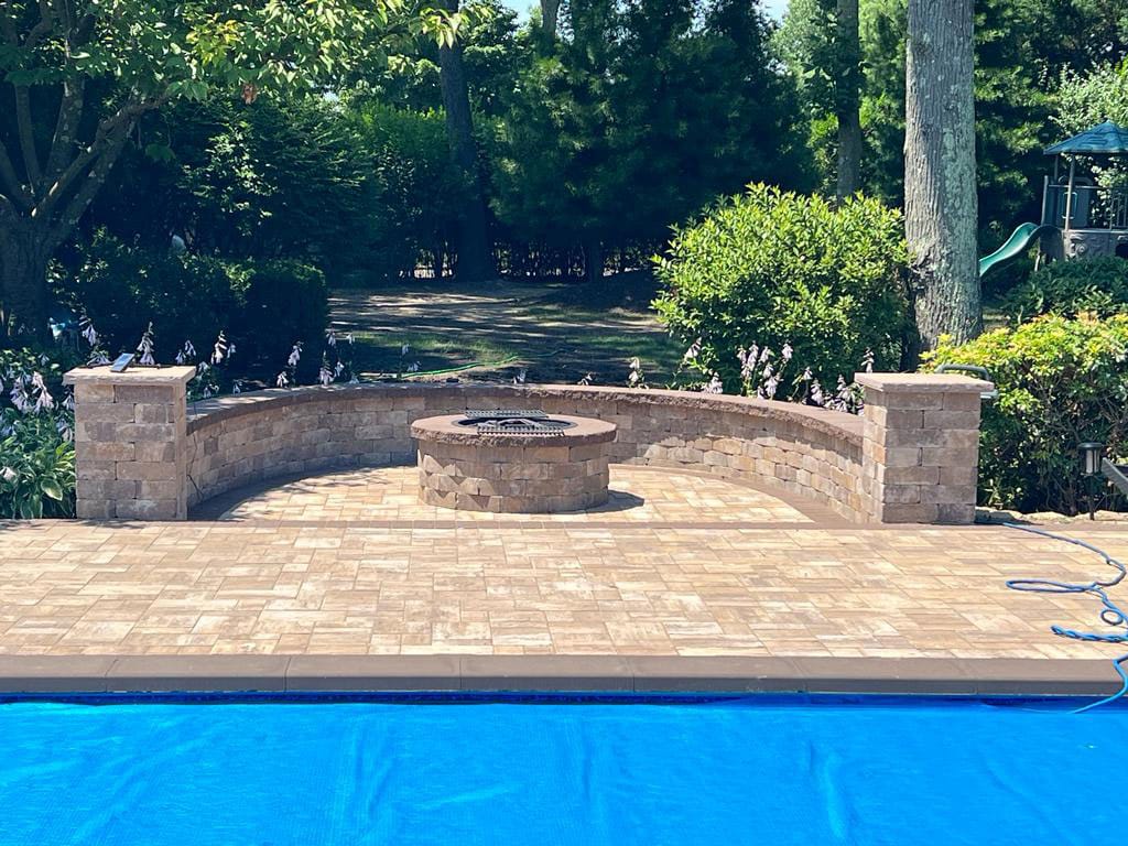 Paver patio with a fire pit and seating wall