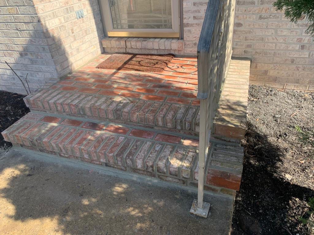 Brick front steps with a railing